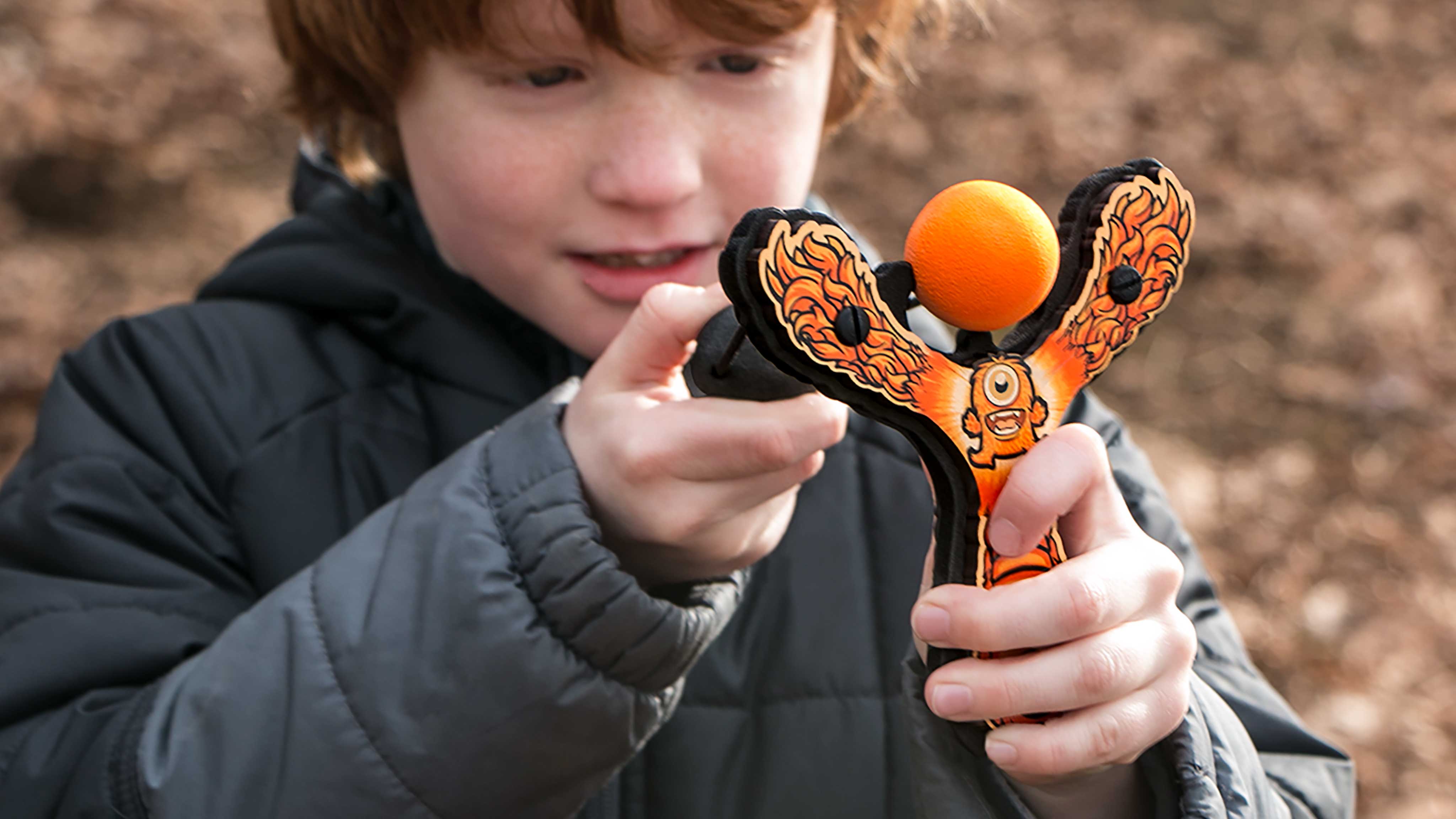 Kid shooting Mischief Maker Slingshot by Mighty Fun! outside