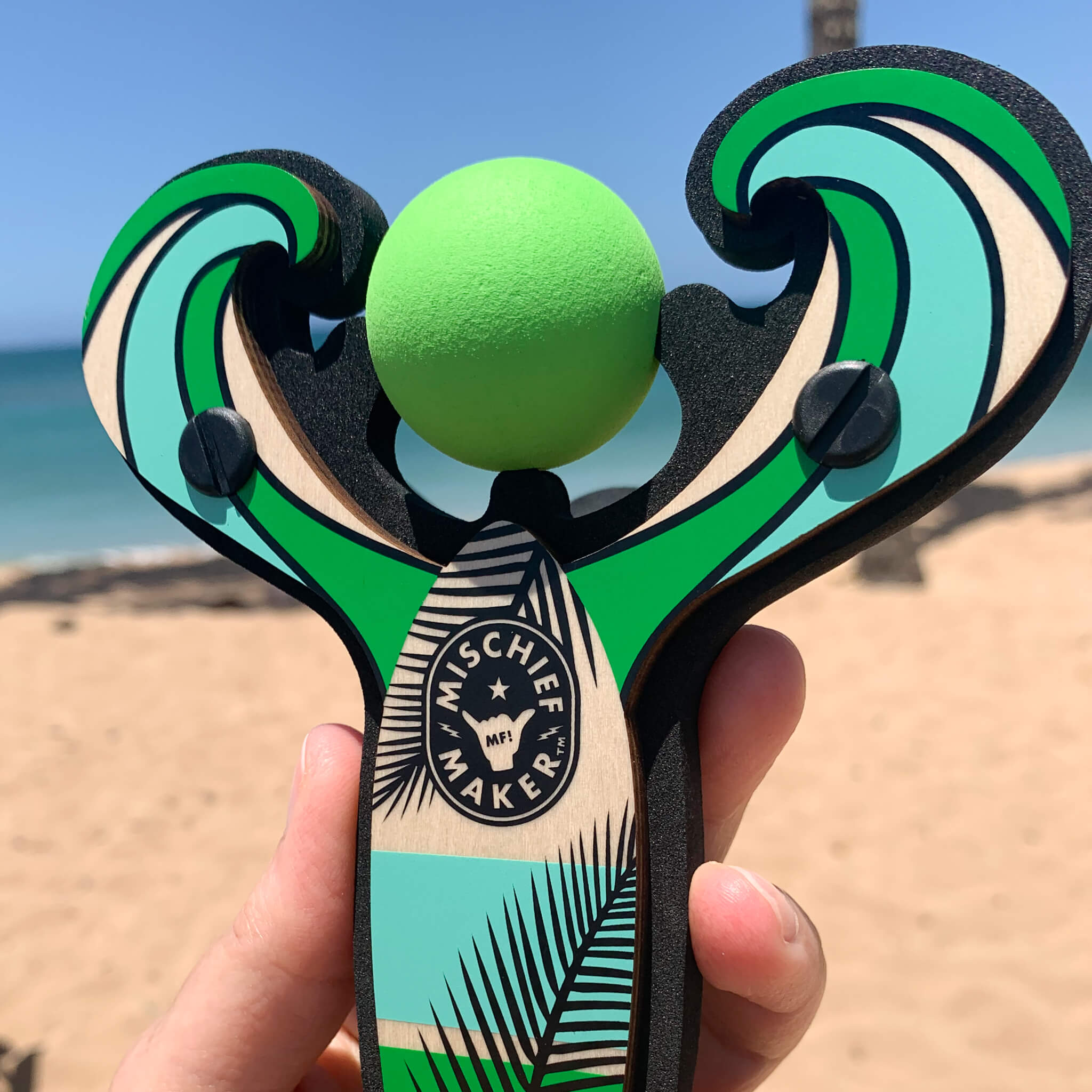 Green Surf’s Up toy slingshot with ball foam ball by the ocean. Mischief Maker by Mighty Fun!