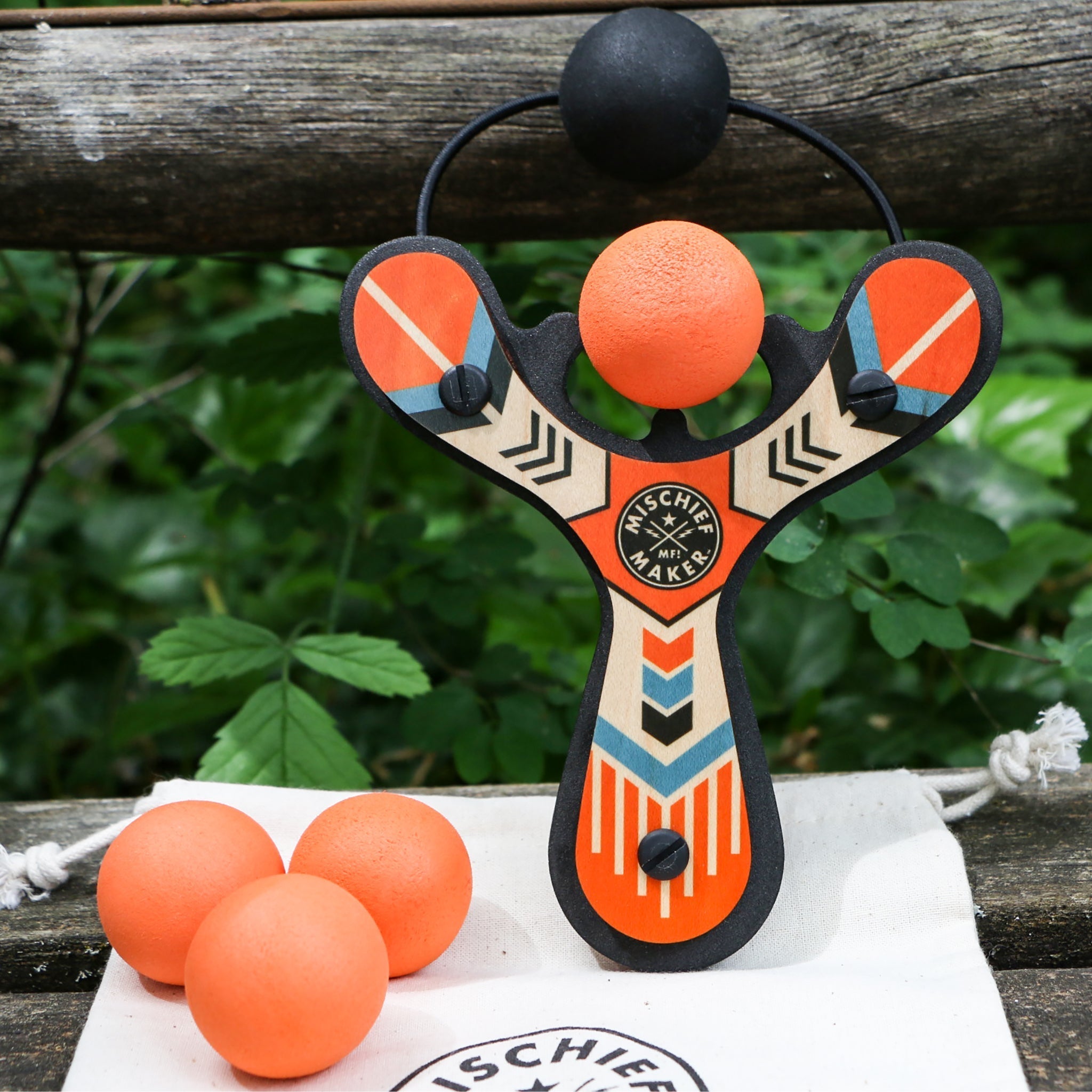 Orange Classic wood slingshot with 4 soft foam balls outside. Mischief Maker by Mighty Fun!