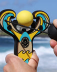 Yellow Surf’s Up toy slingshot being launched by the ocean. Mischief Maker by Mighty Fun!