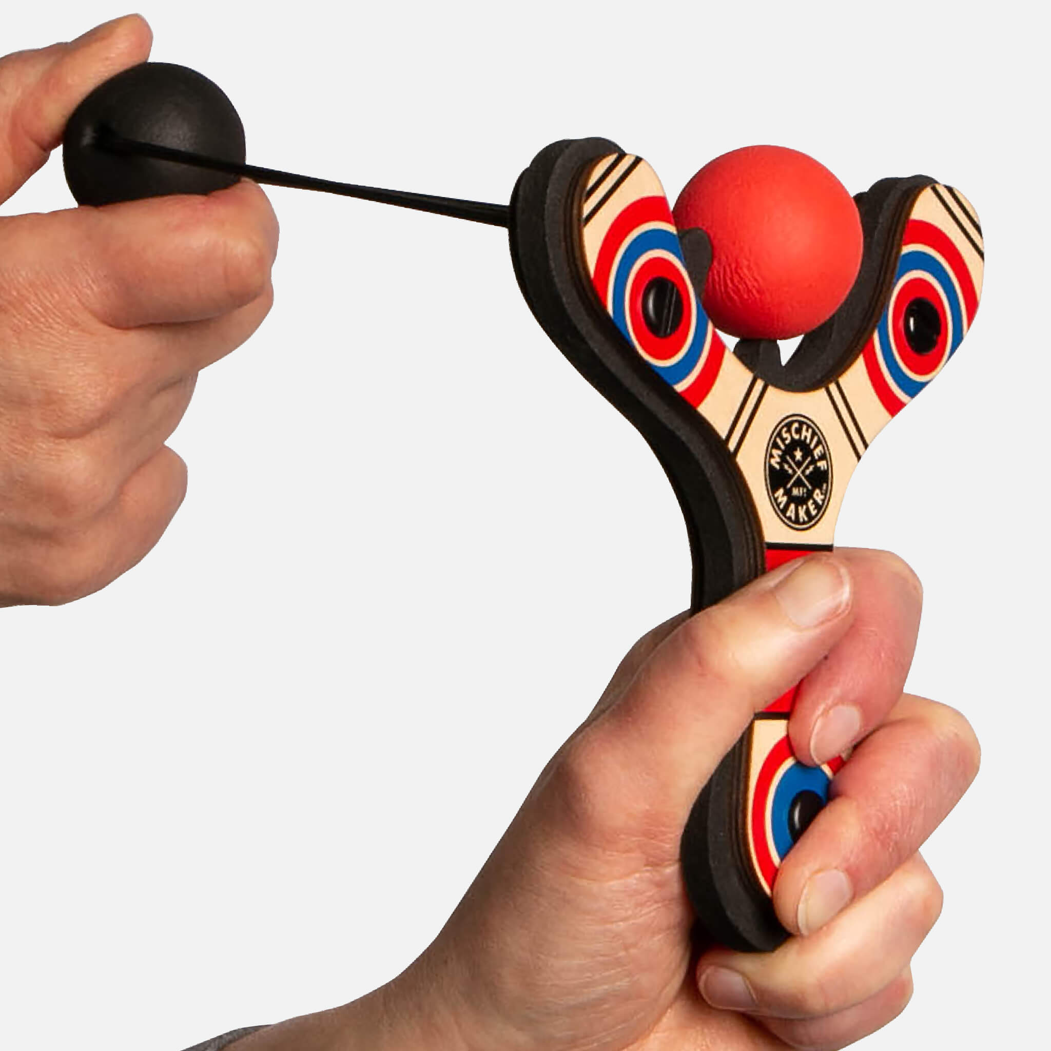 Red Classic wood slingshot being launched. Mischief Maker by Mighty Fun!