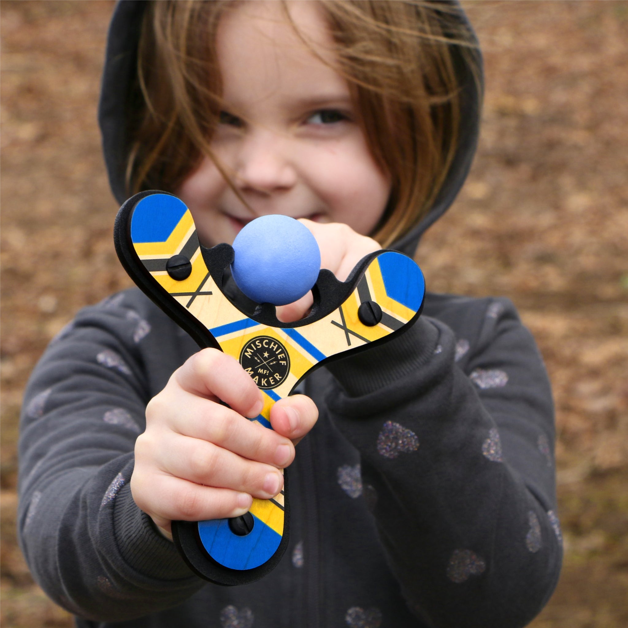 Blue Classic toy slingshot being shot by 6 year old girl. Mischief Maker by Mighty Fun!