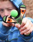 Green Classic wood slingshot being shot by 8 year old boy. Mischief Maker by Mighty Fun!