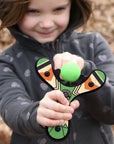 Green Classic wood slingshot being shot by 5 year old girl. Mischief Maker by Mighty Fun!