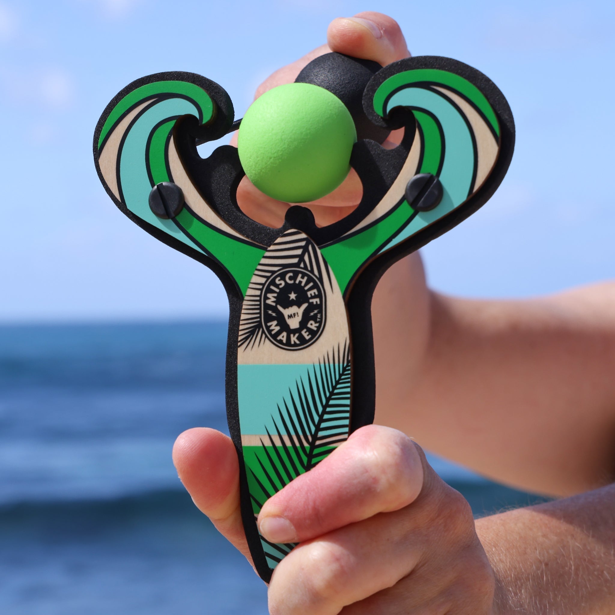 Green Surf’s Up toy slingshot being launched by the ocean. Mischief Maker by Mighty Fun! 