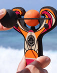 Orange Surf’s Up toy slingshot being launched by the ocean. Mischief Maker by Mighty Fun!