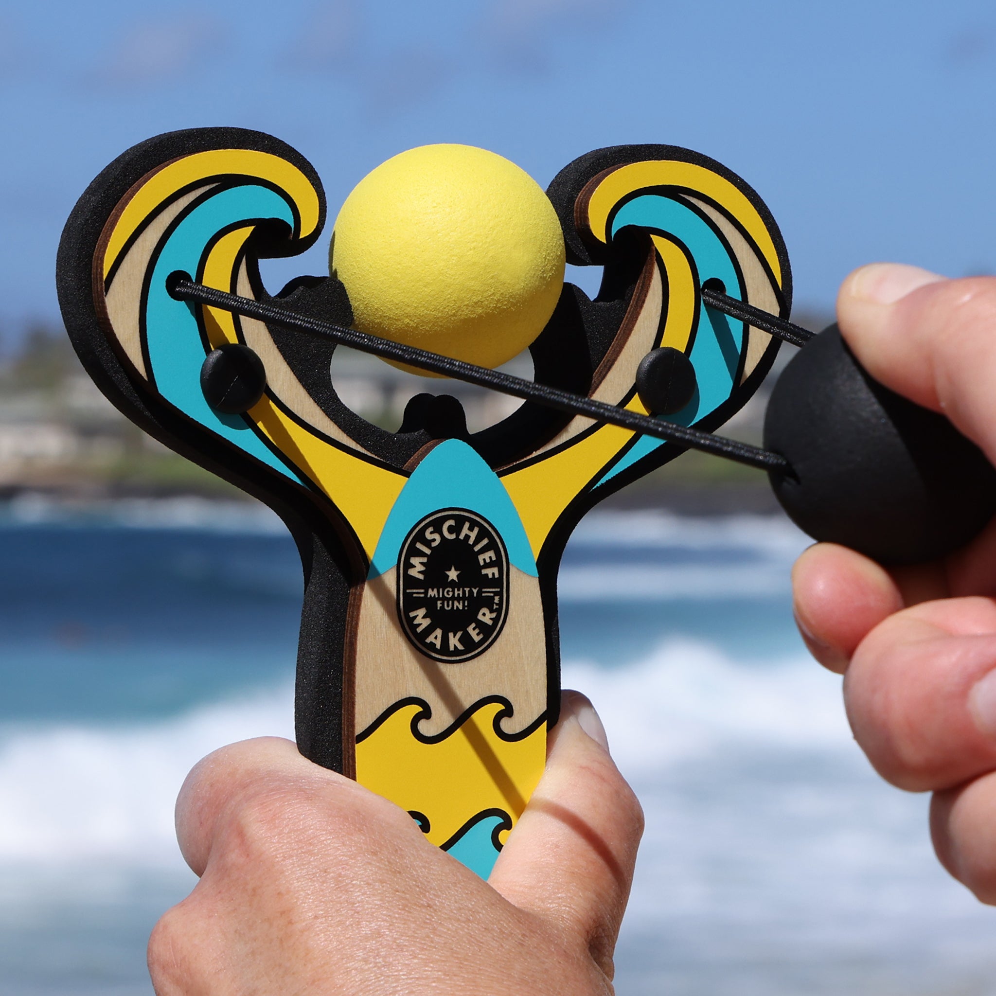 Yellow Surf’s Up toy slingshot being launched by the ocean. Mischief Maker by Mighty Fun!